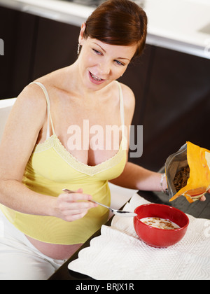italian 7 months pregnant woman eating milk and cereals. Vertical shape, side view Stock Photo