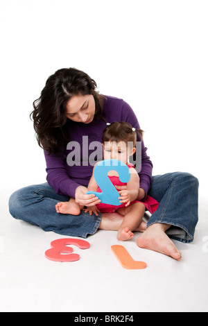 Mother, nanny, or teacher teaching baby to learn how to count one, two, three, with numbers in a playful way. Stock Photo
