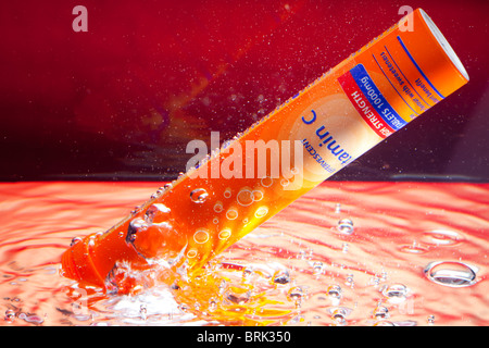 A tube of effervescent vitamin C tablets under water and creating fizz and bubbles Stock Photo