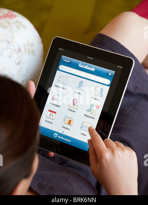 Woman using Facebook social networking app on iPad tablet computer Stock Photo