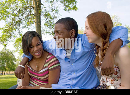 small group of 3 multi-ethnic friends playing in the park and laughing together having fun Stock Photo