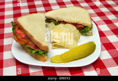 bacon, lettuce and tomato sandwich with potato chips and a pickle Stock Photo