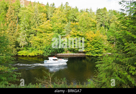 Motor boat heading north on the Caledonian Canal between Loch Lochy and Loch Oich in Highland Scotland Stock Photo