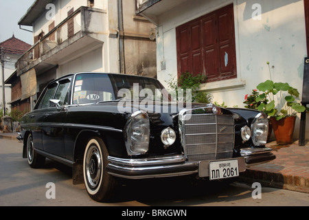 A black fully restored 1960's era Mercedes Benz 280 S automobile is parked on a street in Luang Prabang, Laos.