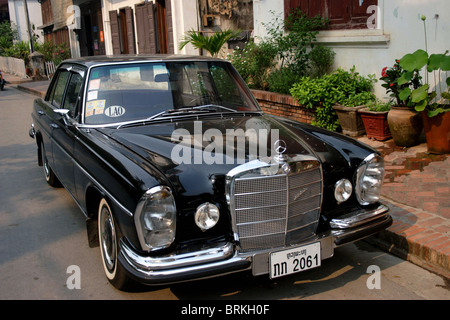 A black fully restored 1960's era Mercedes Benz 280 S automobile is parked on a street in Luang Prabang, Laos.