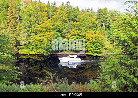 Motor boat heading south on the Caledonian Canal between Loch Lochy and Loch Oich in Highland Scotland Stock Photo