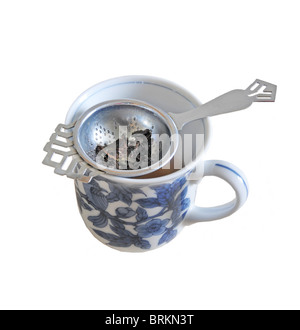 a tea leaf strainer sitting on a cup full of tea leaves. Stock Photo