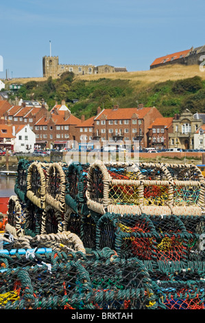 Close up of crab lobster pots pot stacked on quayside and St Mary's church in the background Whitby Harbour North Yorkshire England UK United Kingdom Stock Photo