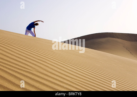 Woman doing yoga in the Maspalomas sand dunes Stock Photo