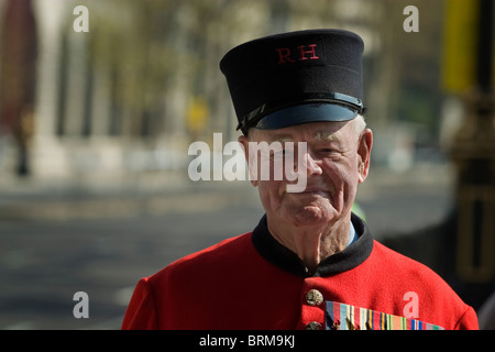 Chelsea Pensioner, an old soldier and war veteran in uniform poses for the camera in a London street during the London Marathon Stock Photo