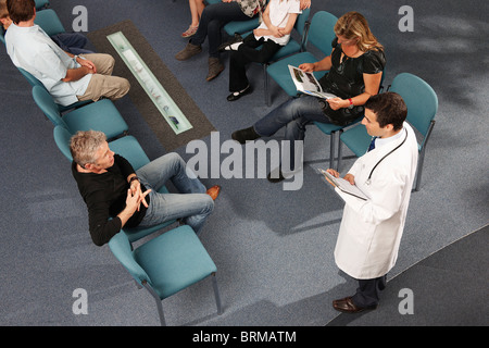 Doctor and patients in waiting area Stock Photo