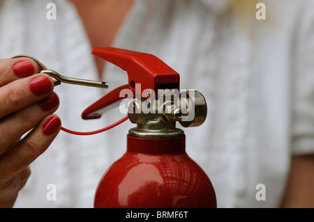 Removing the metal safety pin from a fire extinguisher Stock Photo