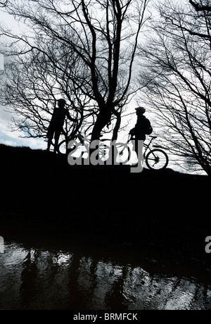 Silhouette couple biking in countryside Stock Photo