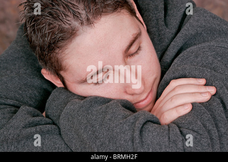 man resting eyes closed skeeping on his arms Stock Photo