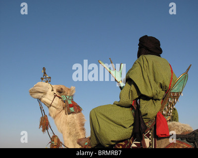 Tuareg man on a camel dressed in traditional robes watching a performance at the annual Festival in the desert Stock Photo