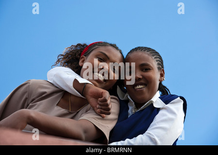 Two local women in Western dress smiling and hugging each other Stock Photo