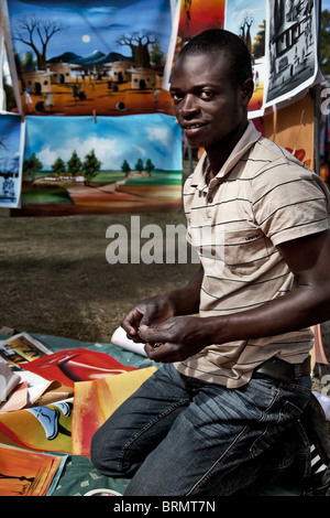 Young African man kneeling at art stall Stock Photo