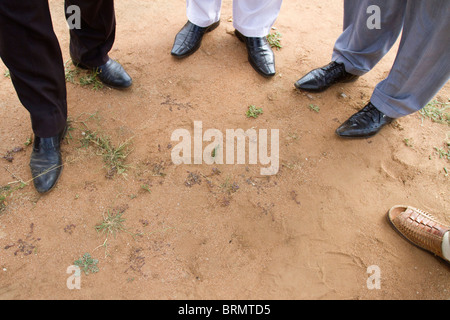 The feet of a group of African businessmen standing in a circle during a site meeting in rural South Africa Stock Photo
