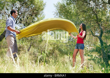 Happy couple laying out picnic blanket Stock Photo