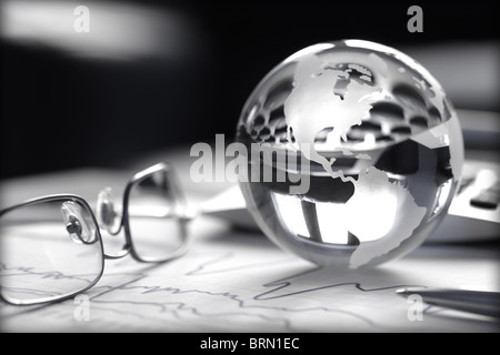 Toned image of glass globe with stock charts, calculator and spectacles