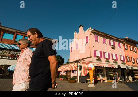 Street Scene with Two Men and Brightly Painted Colourful Houses in Historic Town Centre of Caorle, Veneto, Italy Stock Photo