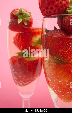 Champagne flutes containing champagne and strawberries, close-up Stock Photo