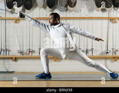 Fencer in white fencing uniform practicing in a gym Stock Photo