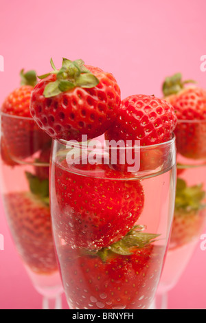 Champagne flutes containing champagne and strawberries, close-up Stock Photo