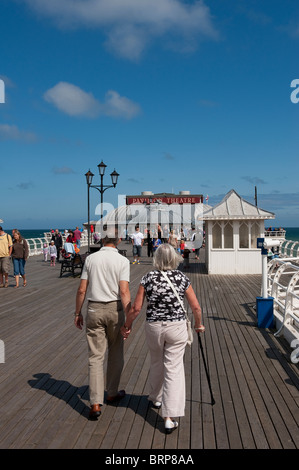 Elderly couple walking along Cromer pier on a summer day in Norfolk, East Anglia, England. Stock Photo