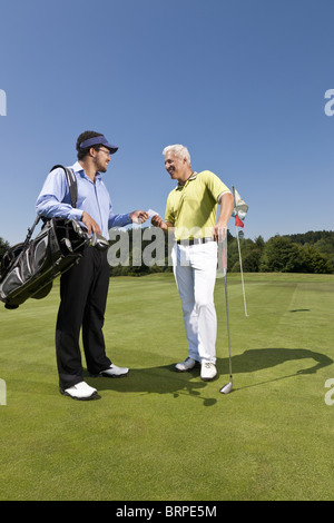 Golfer giving his card to the caddy Stock Photo
