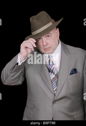 serious looking older gentleman tipping his fedora over a black background Stock Photo