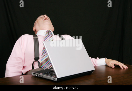 business man sleeping on the job while working at his laptop over black Stock Photo