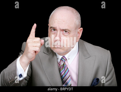 a middle aged business executive pointing a finger over a black background Stock Photo