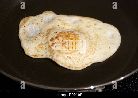cooking an over easy egg in a frying pan Stock Photo