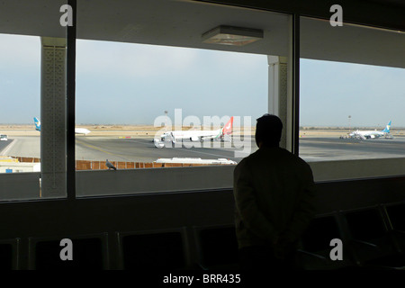 Man looking through a window at the airport Stock Photo