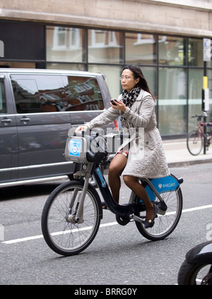 woman texting on phone whilst riding boris bike in London Stock Photo