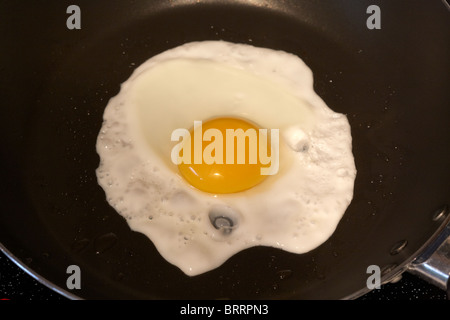 cooking a sunnyside up fried egg in a frying pan Stock Photo