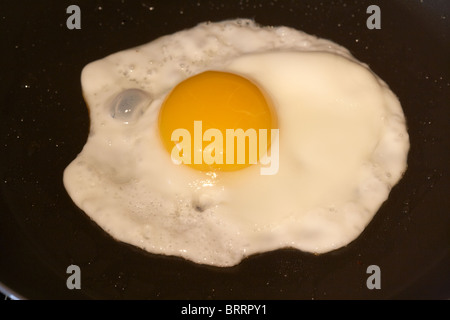 cooking a sunnyside up fried egg in a frying pan Stock Photo