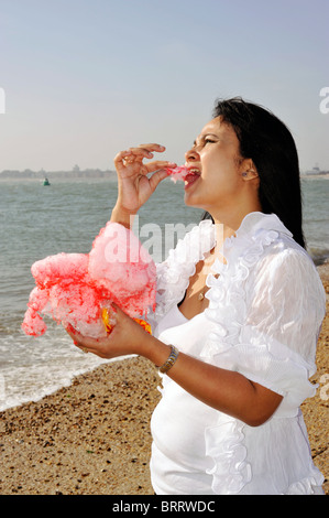 young woman eating candy floss on the beach southsea england uk Stock Photo