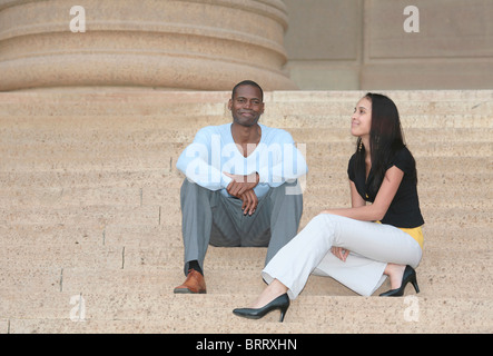 a man and woman two friends talking on the stairs at an old building Stock Photo