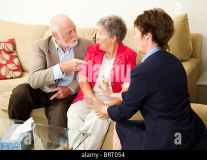 Senior couple in therapy, working out their problems with a counselor. Stock Photo