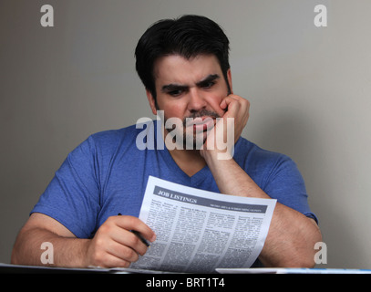 Young man reading job listings in hopes of finding employment during recession, October 2, 2010 Stock Photo