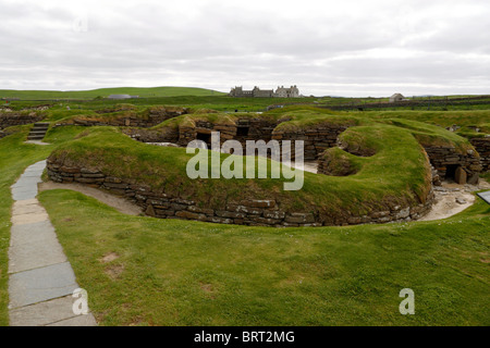 View of the Neolithic village of Skara Brae with Skaill House in background Stock Photo