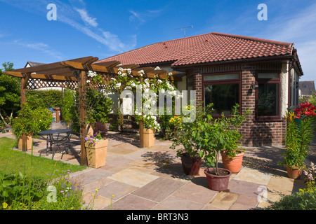 Back garden of bungalow with pergola and patio, England Stock Photo