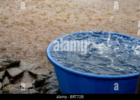 It is raining. Bucket with rain water 