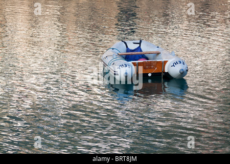 small boat floating in calm water at clovelly harbour in north devon uk Stock Photo