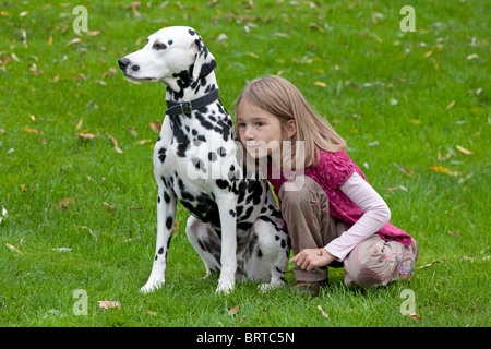 portrait of a young girl crouching beside her dalmatian Stock Photo