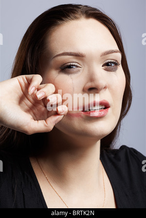 portrait of beautiful crying girl with smeared mascara drying her tears and smearing lipstick Stock Photo