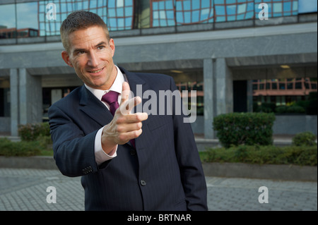 Man in a suit, smiling and pointing hand at someone, business concept Stock Photo