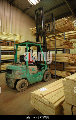 Man operating forklift truck to carry wood planks in a warehouse Stock Photo